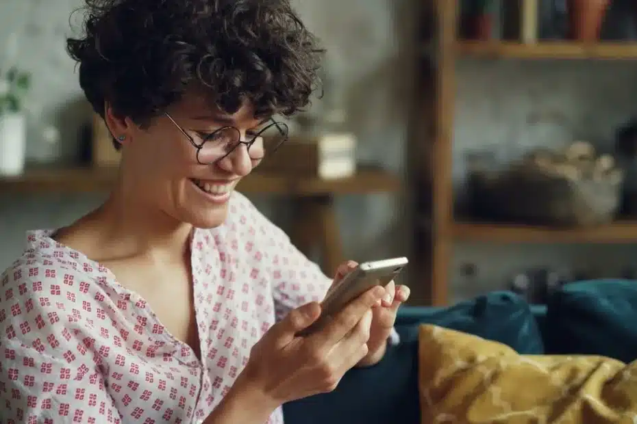 Femme utilisant l’application Vinted sur son téléphone dans un salon.