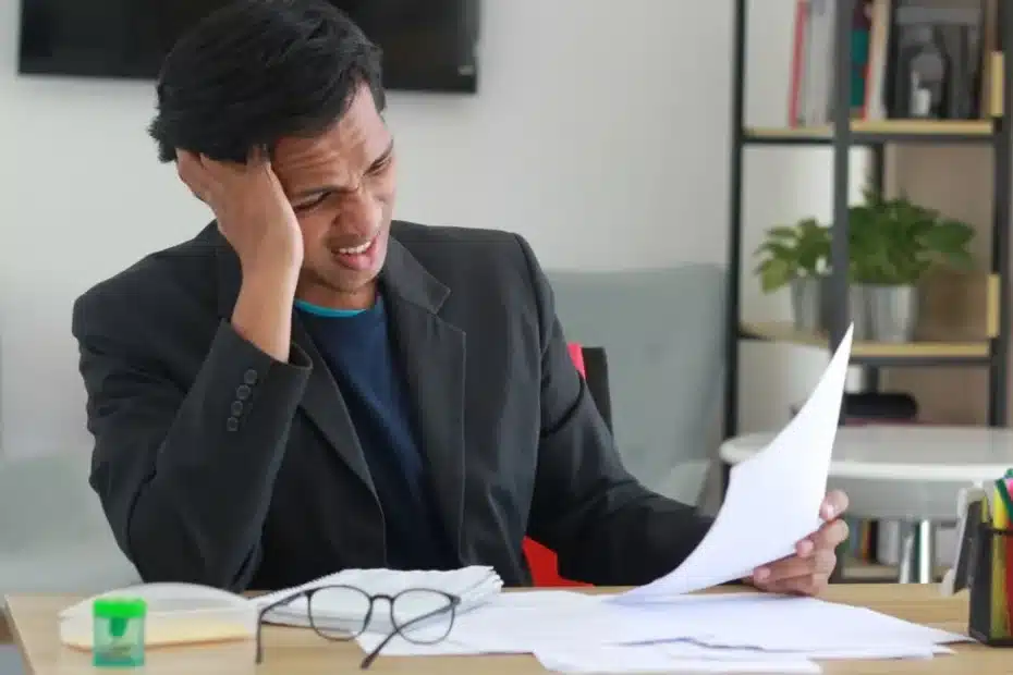 Un jeune homme lit son contrat d’assurance mobile avec inquiétude