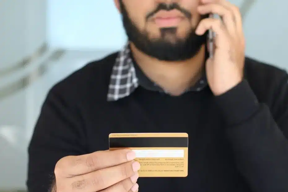 Une main décroche un téléphone fixe rétro sur fond d’écran d’espace client bancaire