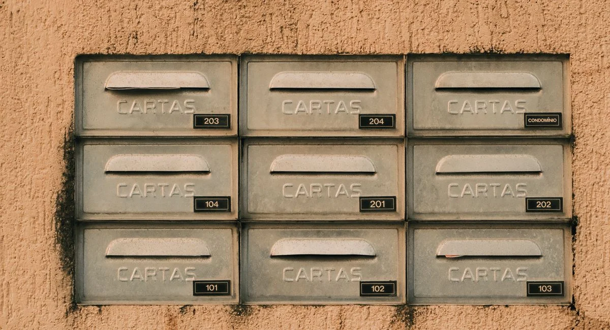 Rustic metal mailboxes labeled 'CARTAS' on a textured wall, Natal, Brazil.